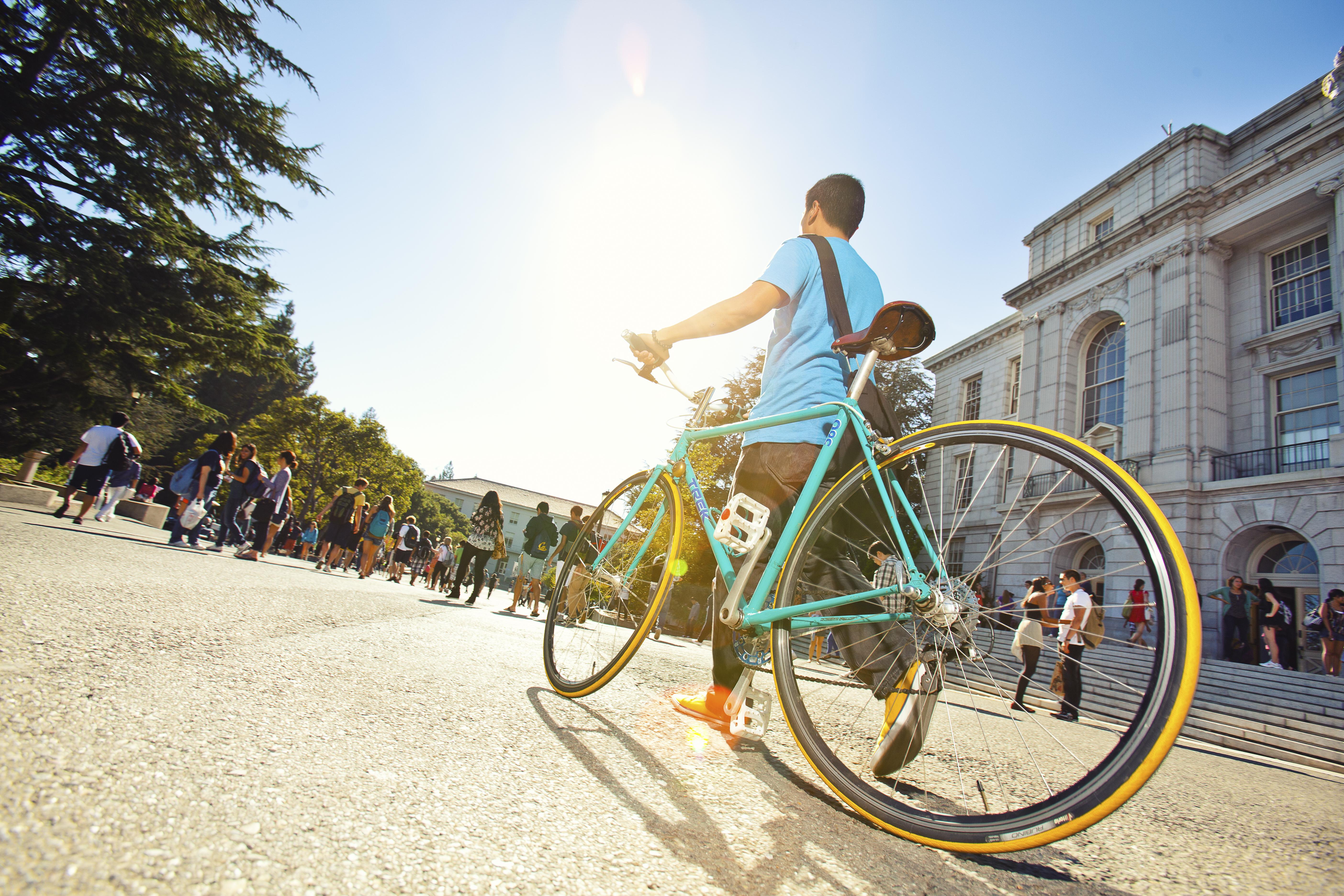 student walking bicycle near Wheeler Hall