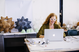 person at computer with constructed geometric forms behind her